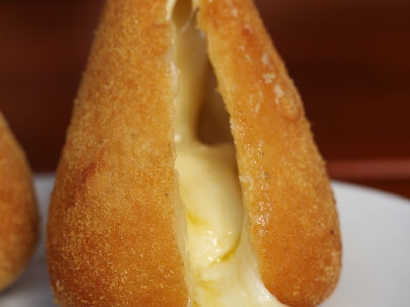 Close da coxinha de queijo aberta, mostrando o recheio